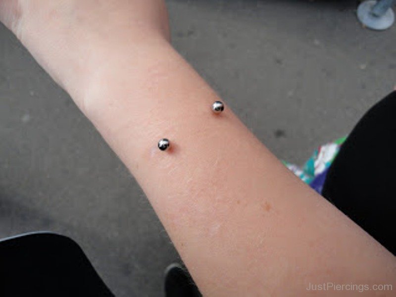 Silver Barbell Piercing With Left Forearm