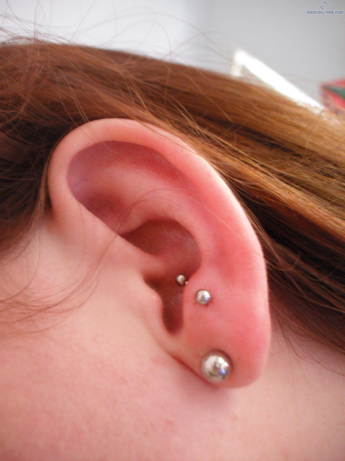 Silver Stud Lobe And Anti Tragus Piercing On Girl Left Ear