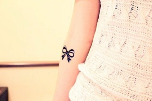 Little Black Ribbon Bow Tattoo On Forearm