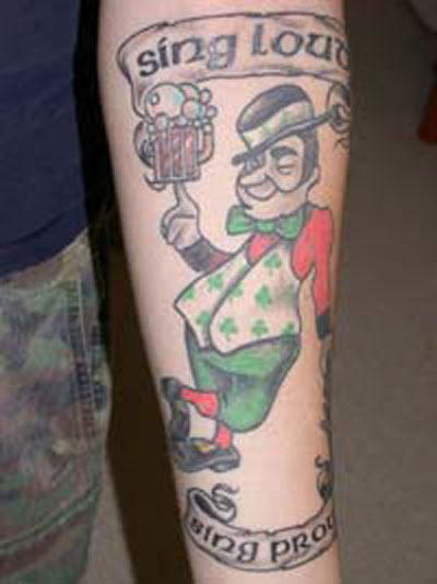 Sing Loud Banner And Leprechaun Tattoo On Forearm