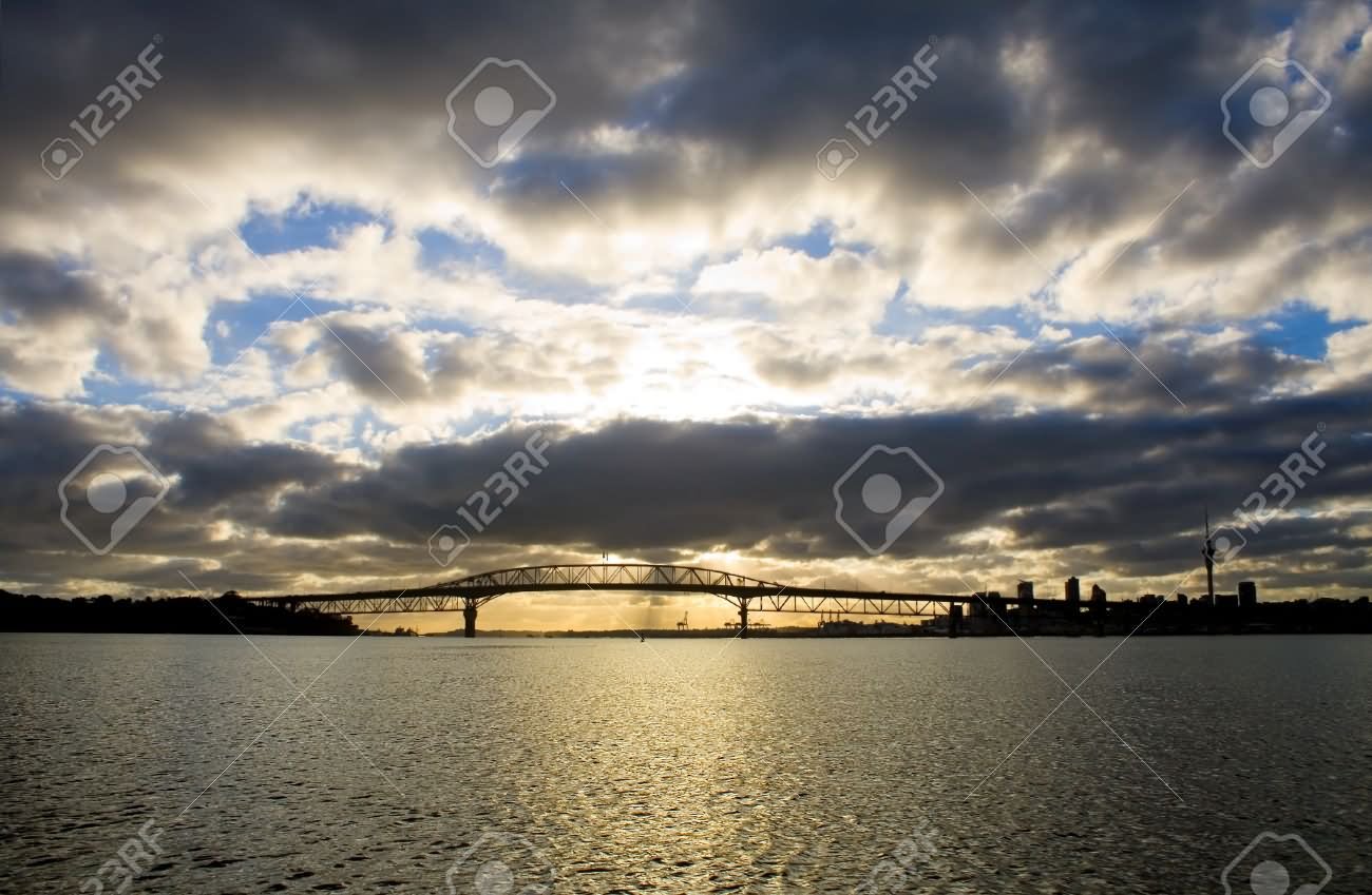 A Dramatic Cloudy Sunrise Over The Auckland Harbour Bridge