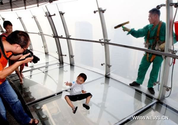 Kid Posing For Photograph Inside The Oriental Pearl Tower While A Worker Cleaning Glasses