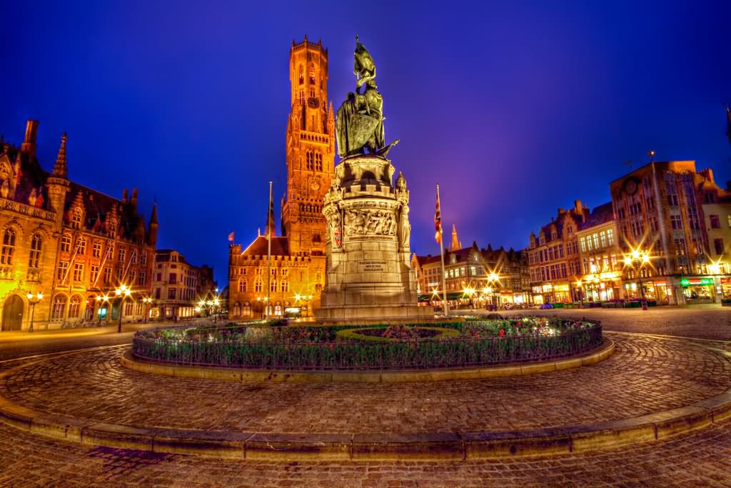 The Statue of Jan Breydel and Pieter de Coninck In Front Of Belfry Lit Up At Night In Bruges, Belgium