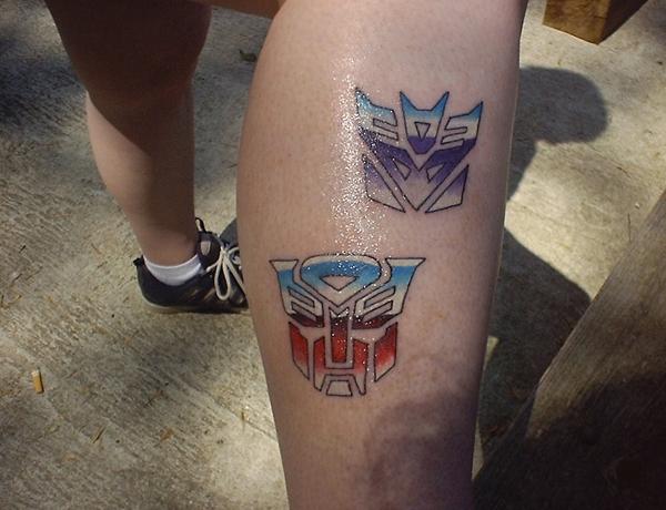 Colorful Two Transformer Logo Tattoo On Leg Calf By Rachel