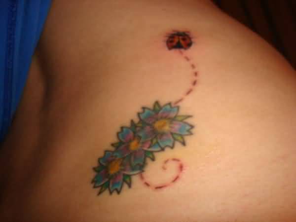 Colored Flowers And Flying Ladybug Tattoo On Lower Back