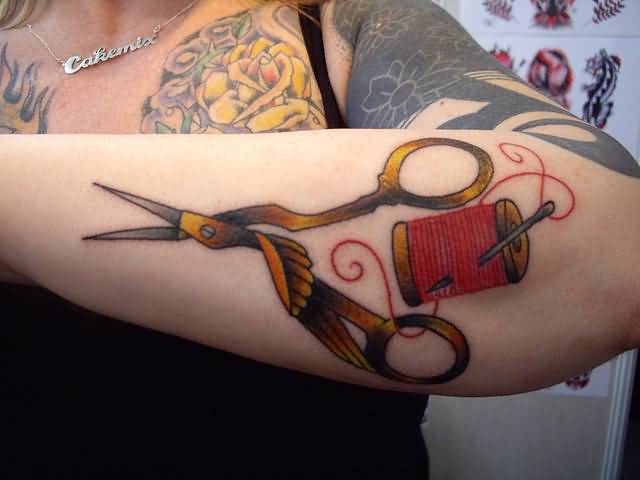 Red Spool And Scissor Craft Tattoo On Left Arm