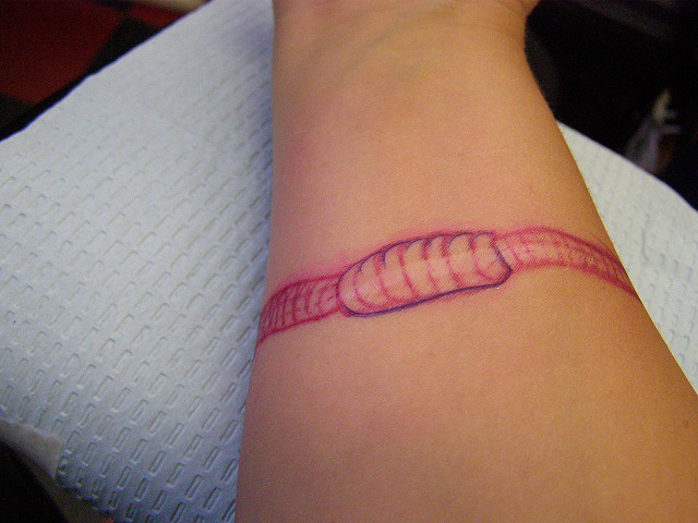 Pink Color Earthworm In Armband Style Tattoo On Forearm