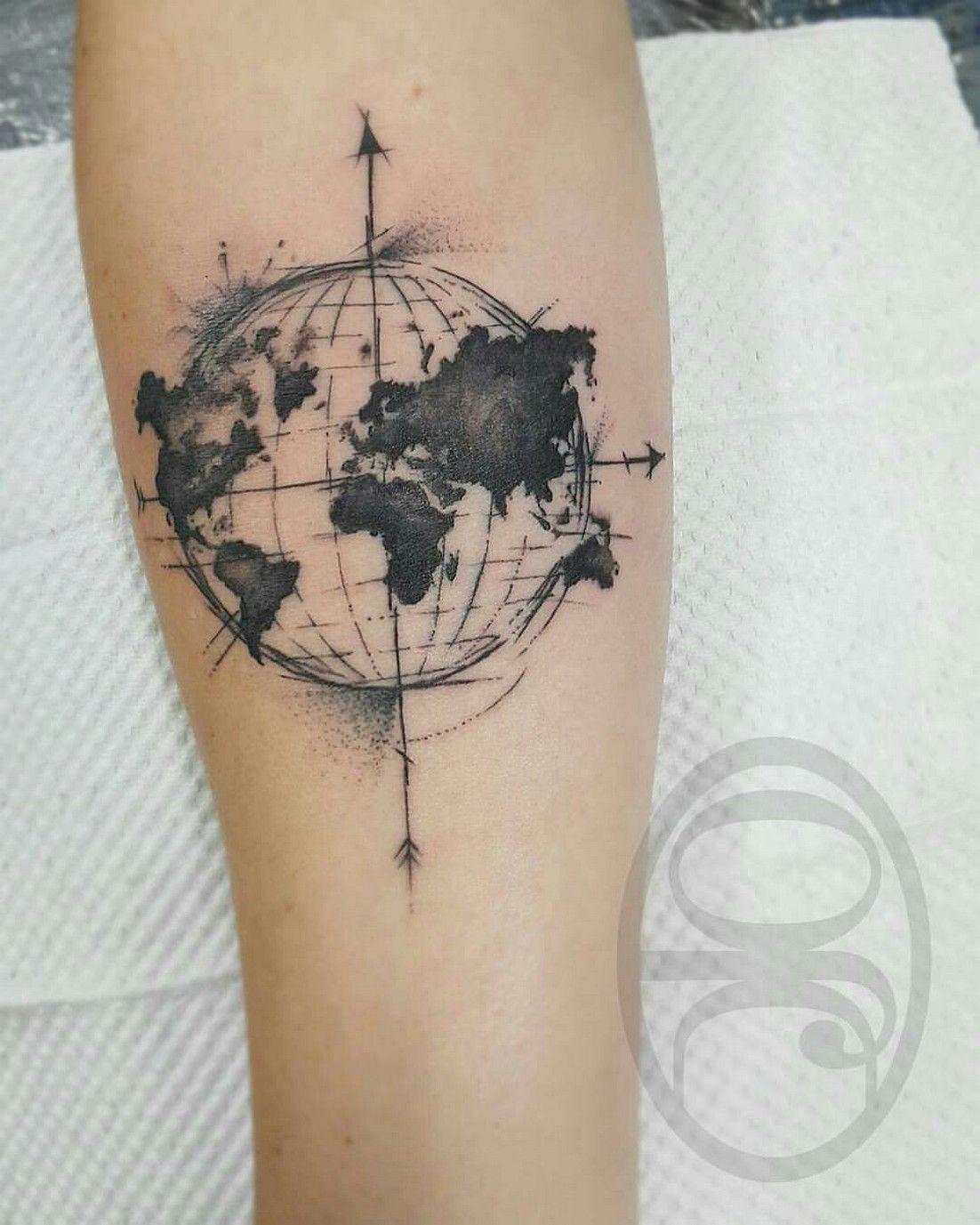 Black globe and compass directions tattoo with map on inner arm