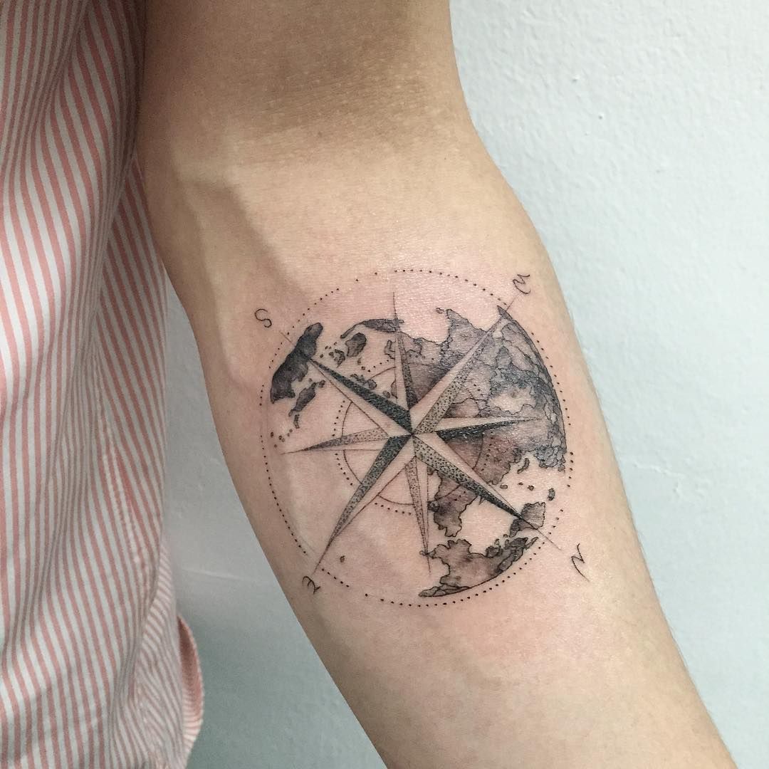 Globe tattoo with compass inside on inner forearm