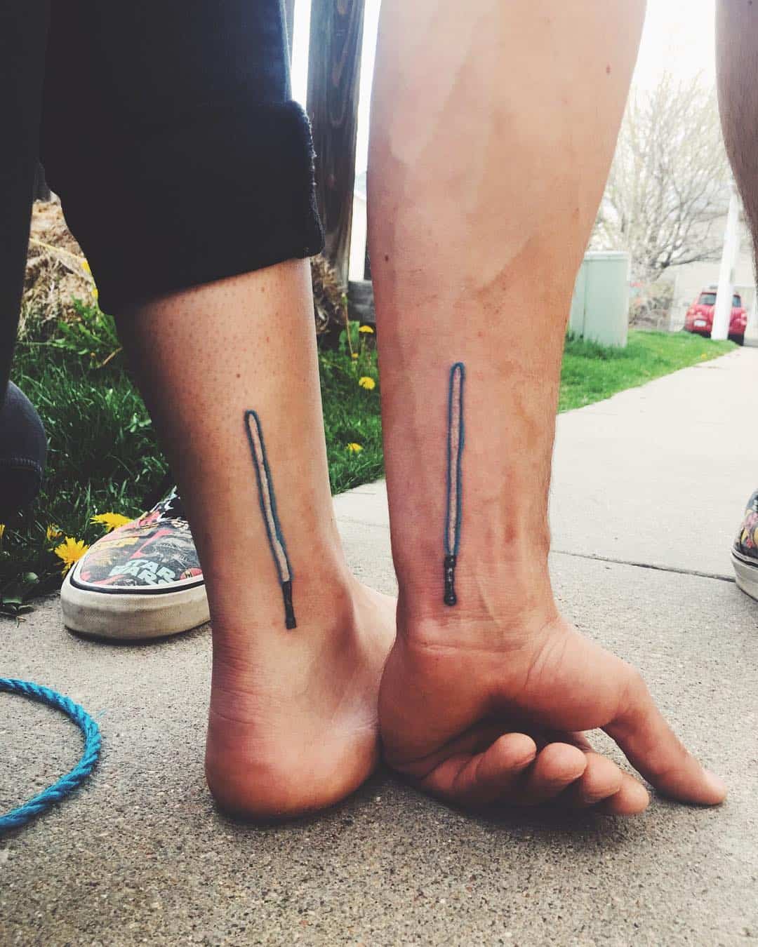 Black and blue light-saber sibling tattoos on inner wrist and right lower leg