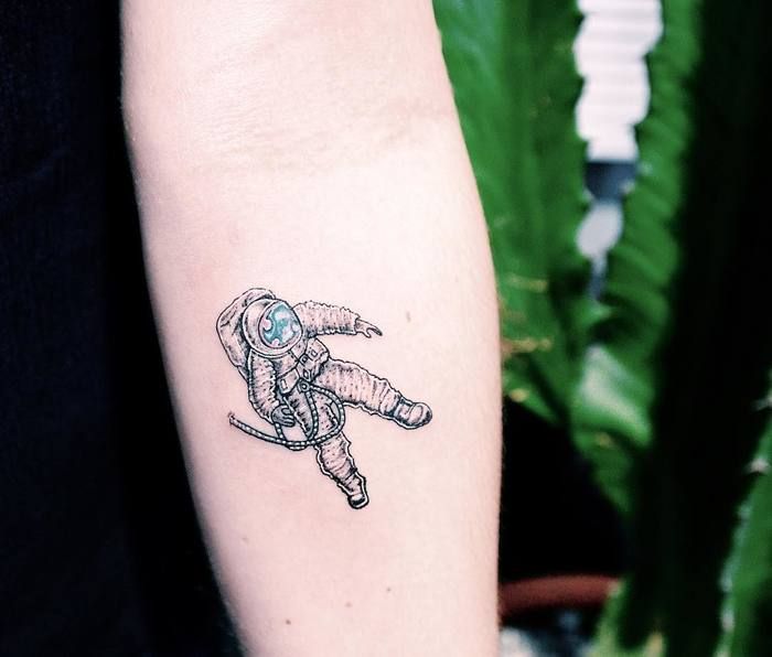 Black and grey astronaut tattoo on inner forearm