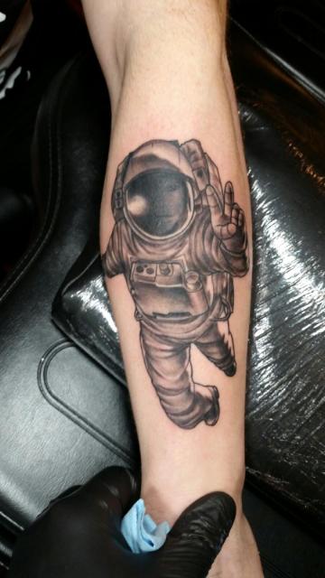 Black and grey shaded astronaut tattoo on upper forearm