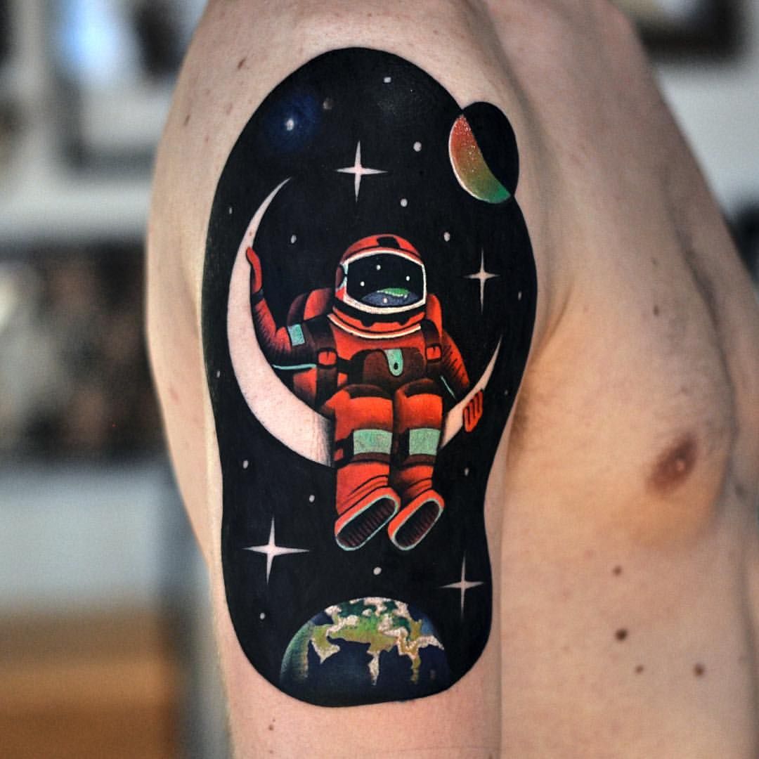 Black and red colored astronaut with universe tattoo on upper arm