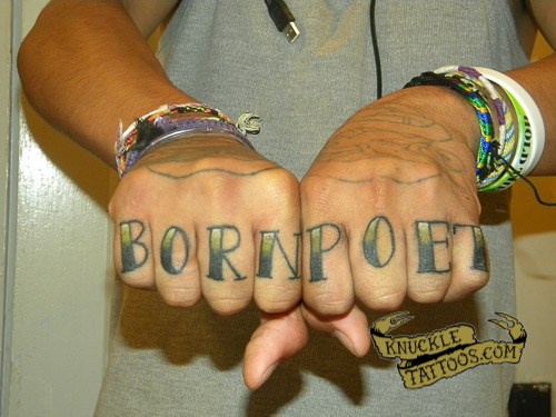 Black and yellow born poet wording knuckle tattoo