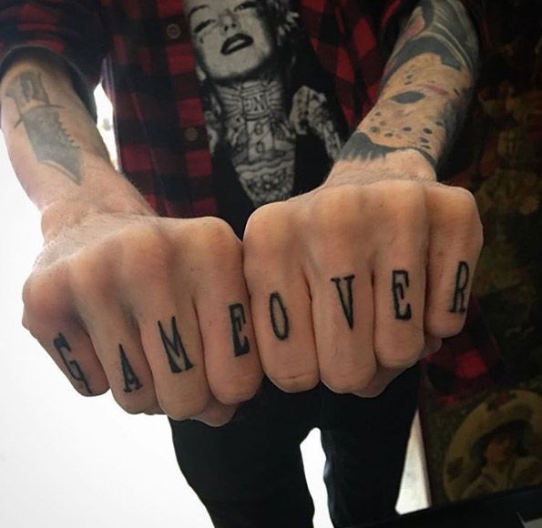 Black game over texted knuckle tattoo