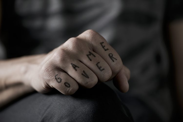 Black game over wording knuckle tattoo