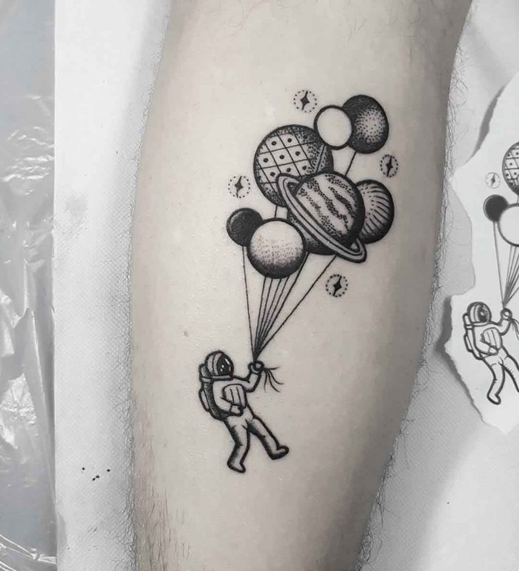 Black shaded astronaut with planets balloon tattoo on forearm