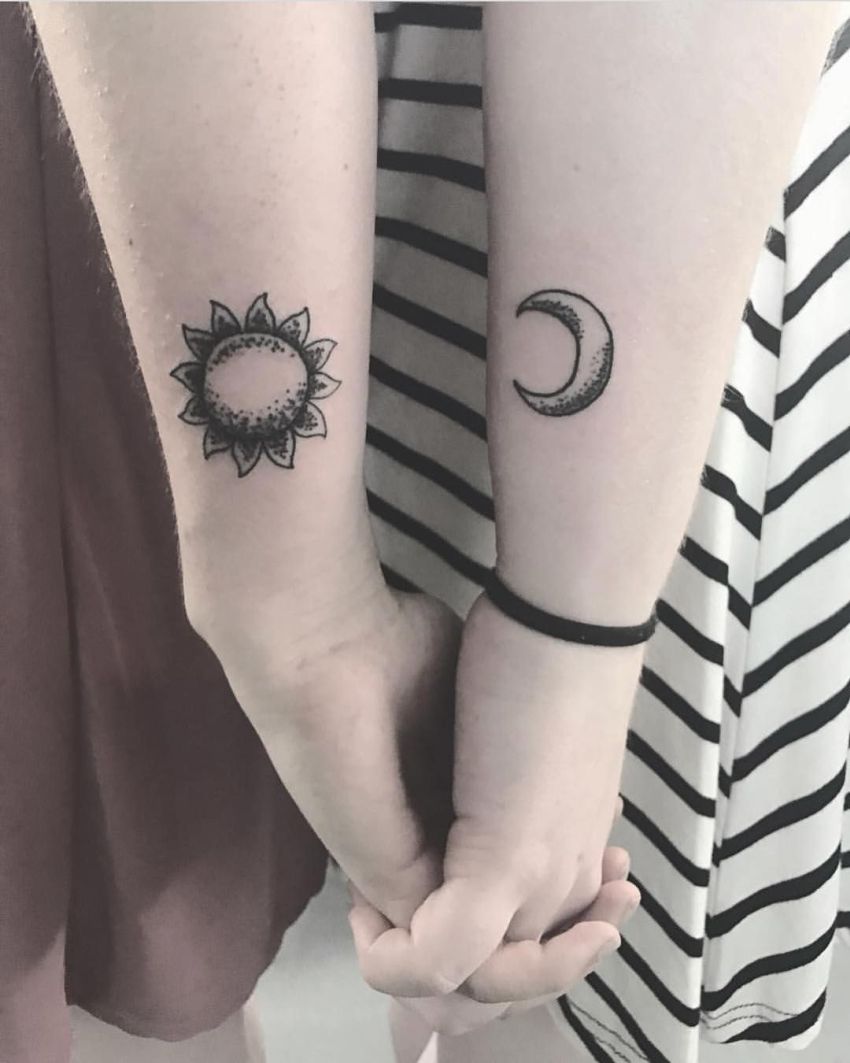 Black sun and moon sibling tattoos on lower forearms