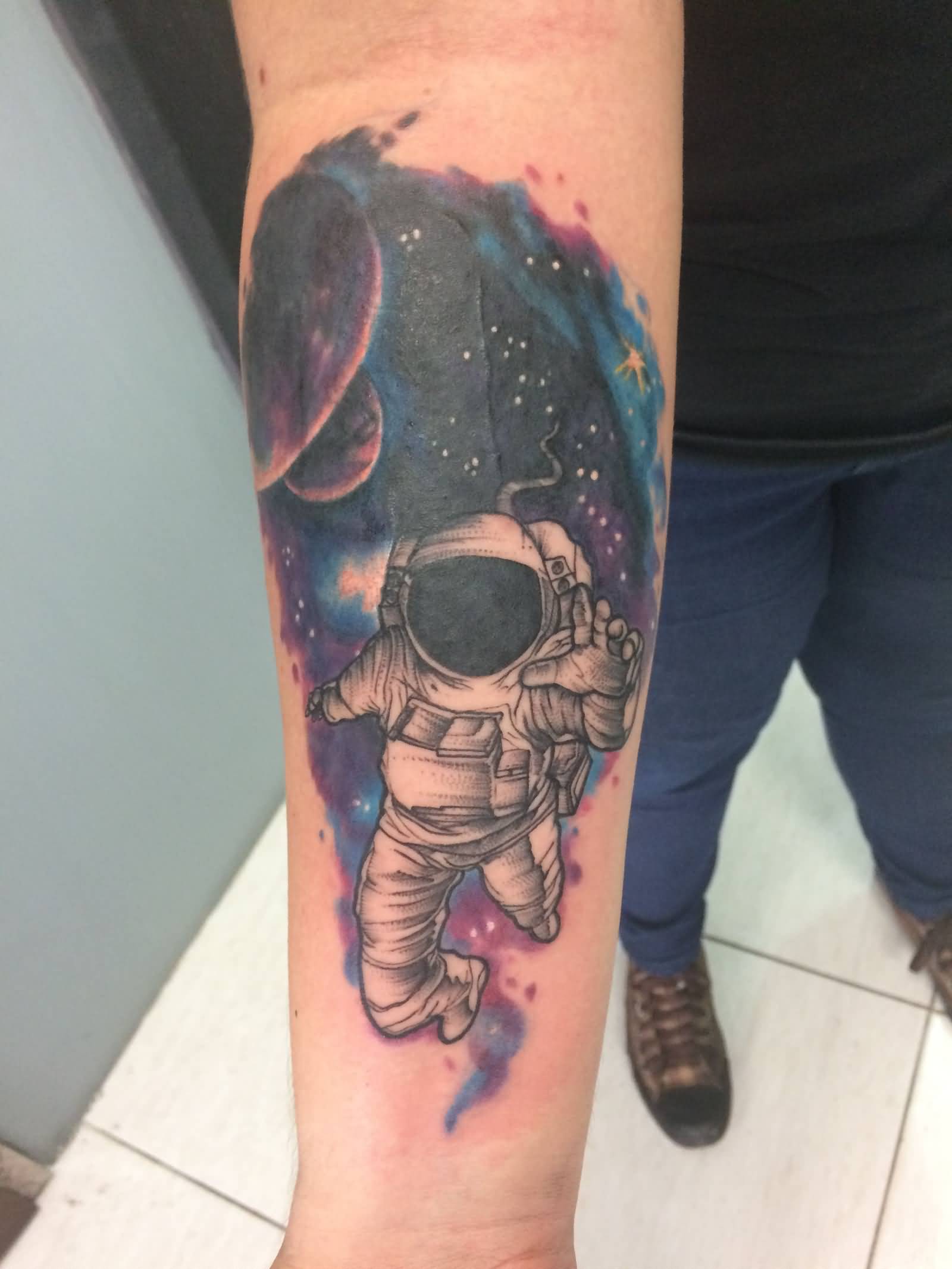 Colored astronaut with universe tattoo on inner forearm