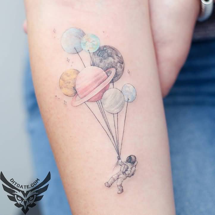 Grey shaded astronaut with colored planets balloon tattoo on inner forearm