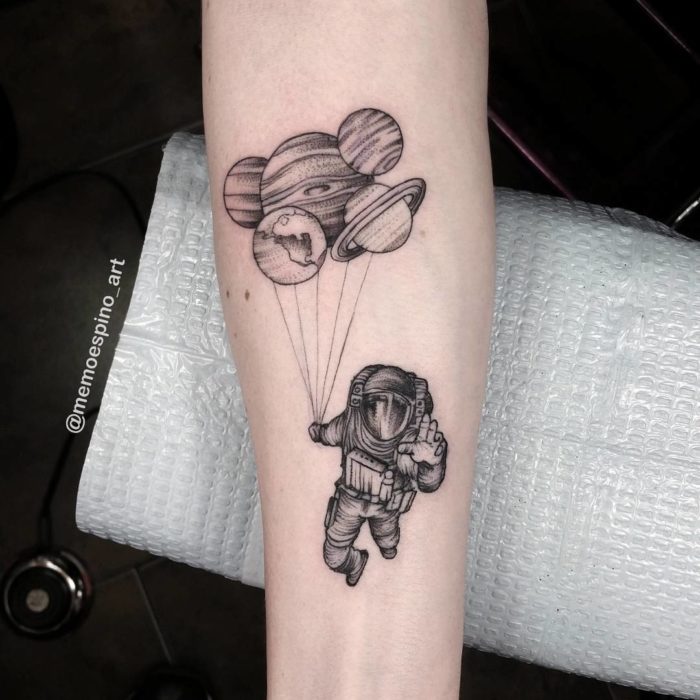 Grey shaded astronaut with planets balloon tattoo on inner forearm