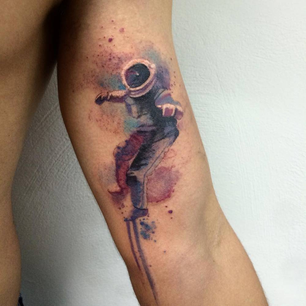 Watercolor astronaut tattoo above elbow