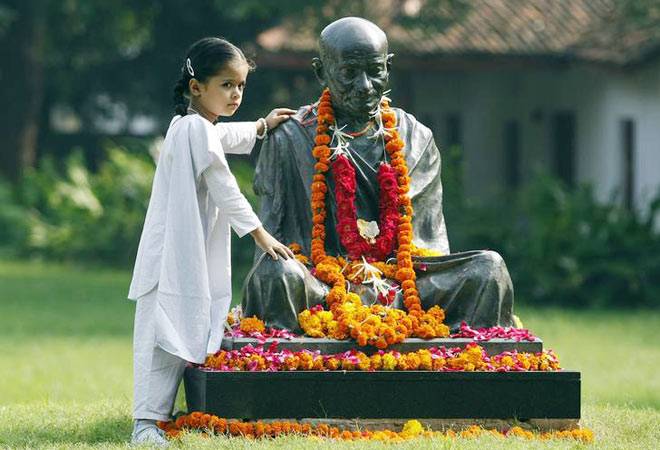 cute little girl with mahatma gandhi statue on Gandhi Jayanti