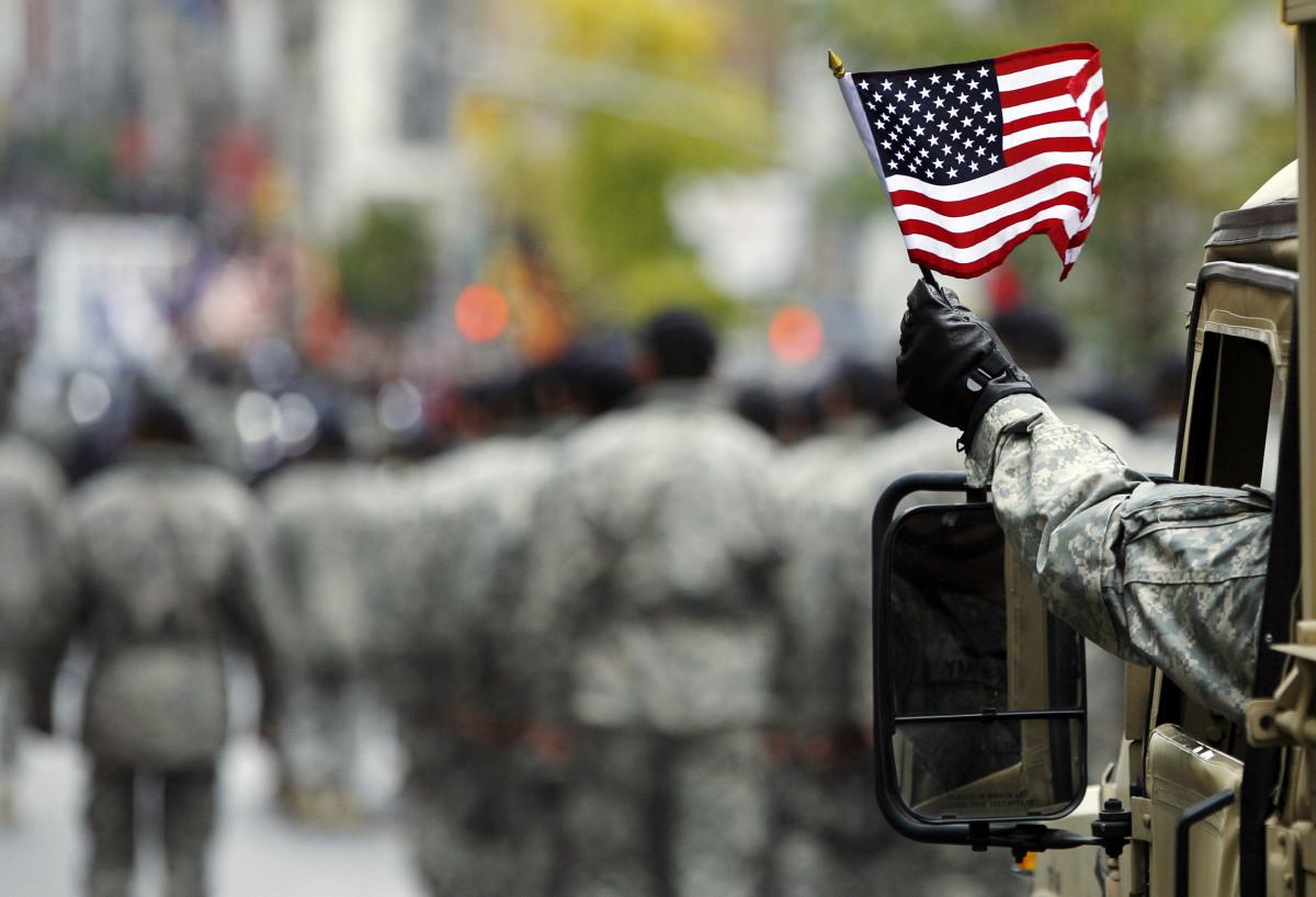 armed serviceman waved american flag during Veterans Day parade